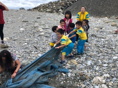 小朋友合力拉出在沙灘裡的帆布垃圾
