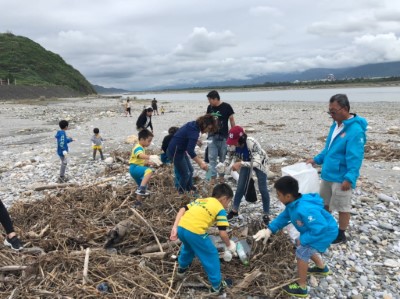 親子合力撿拾花蓮溪口漂流木堆中的寶特瓶與塑膠袋