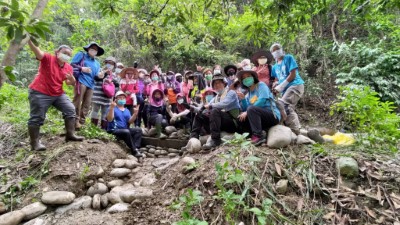 大夥從搬運、挑選、堆砌石頭中交流學習，完成步道邊坡截水溝(拍手)