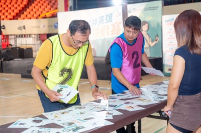 參賽者正在認真挑選桌面上陳列的各種圖卡，這些圖卡代表不同的森林巡護裝備。
