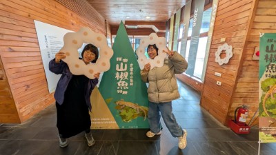 遊客手持特製的「山椒魚卵串」造型板拍照打卡，將形似甜甜圈的珍貴生態影像分享給更多人