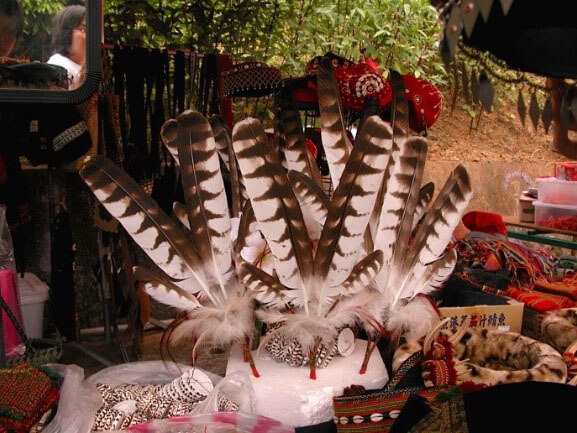在傳統祭儀場合可見販賣熊鷹羽毛的攤販。現今的羽飾文化已經偏離傳統，由此衍生的龐大羽毛市場更加劇熊鷹的狩獵壓力（黃永坤攝）